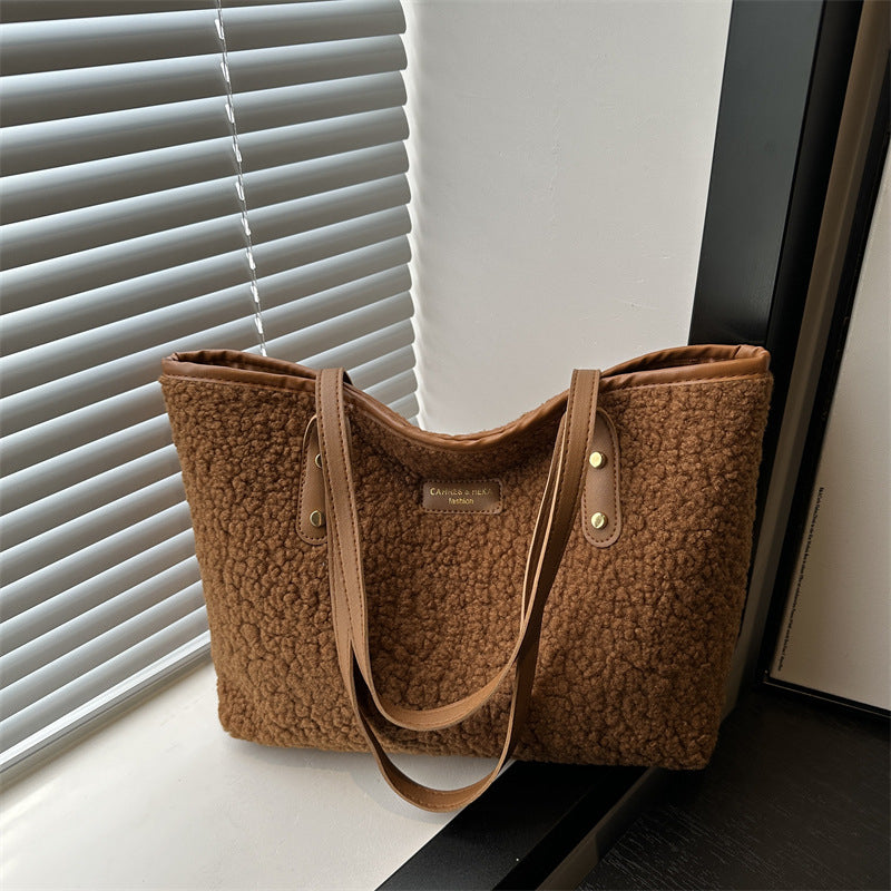 Brown textured tote bag on a surface with blinds in the background